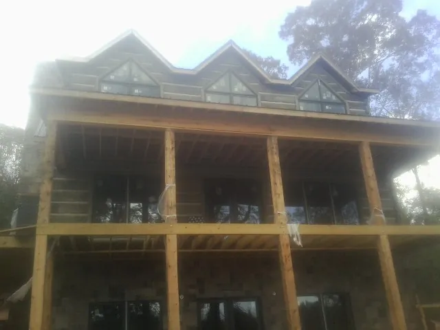 Dormers and porch framing on a large log home under construction — Roof Coating work by our crew in Tomah