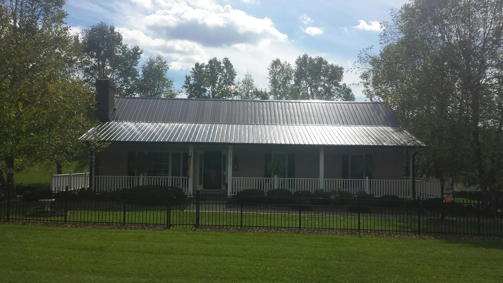 Gray metal roof on a brick ranch with a full width front porch — Gutter Guard Installation work by our crew in Tomah