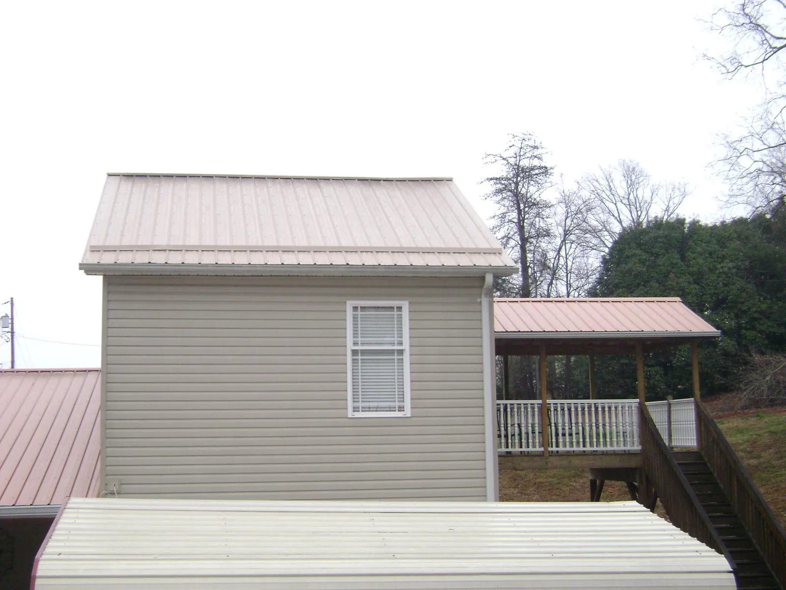 Tan metal roofs on a two story addition and attached porch, from a Roof Replacement job in Tomah